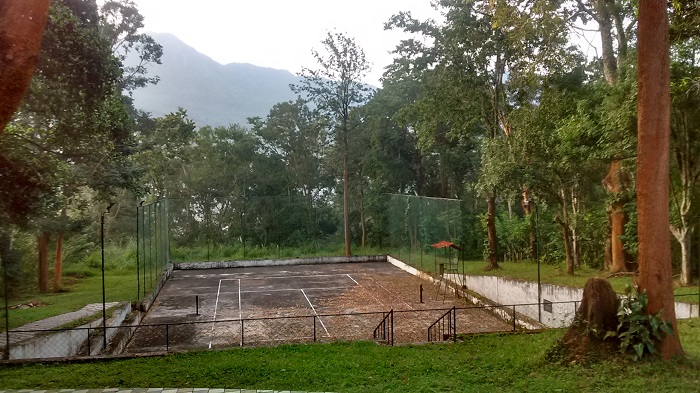 Tennis court at Gudalur Cosmopolitan Club with the forest and the higher hills behind.